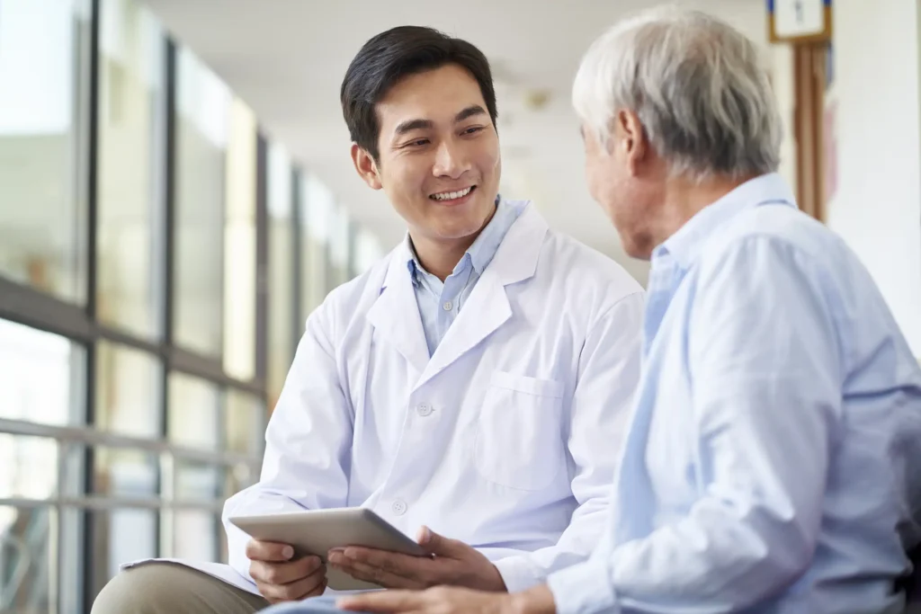 Young asian doctor talking to senior patient in hospital